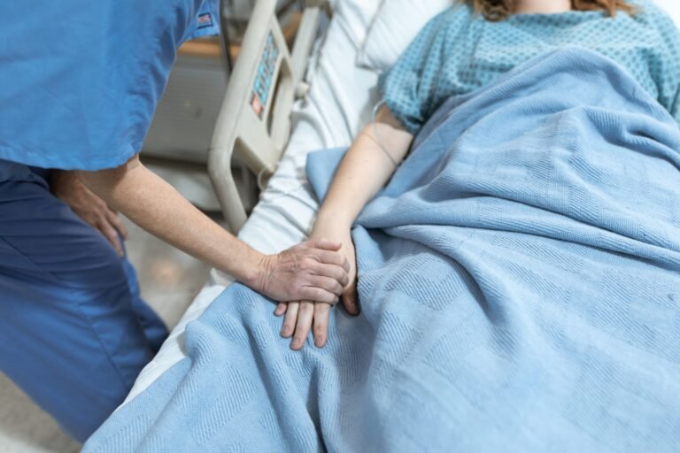 Danke an Pflegepersonal – Pflegekraft hält tröstend die Hand einer Patientin