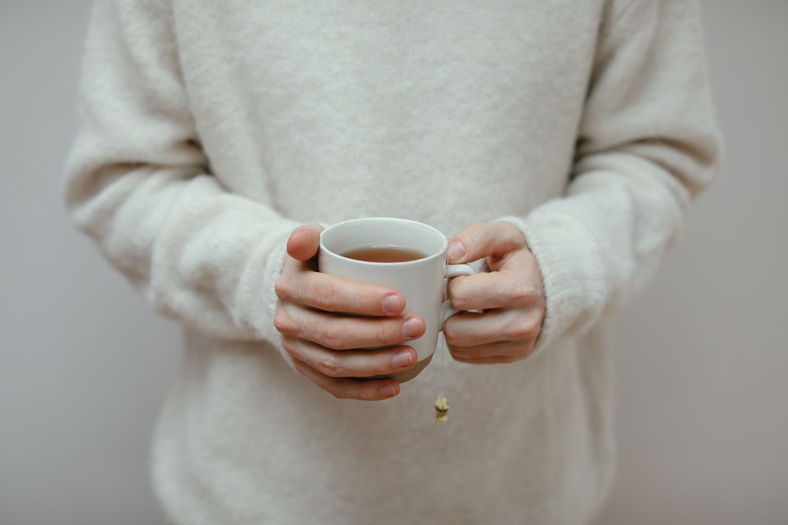 Kurze Genesungswünsche – Hände halten eine warme Tasse Tee