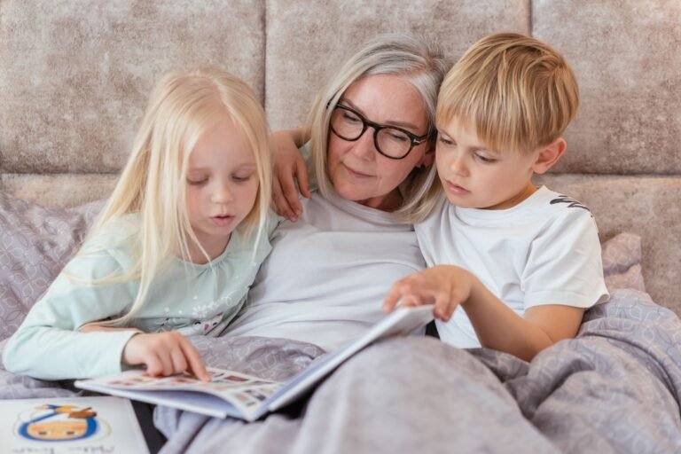 Vorlesen für die Enkel – Großmutter liest zwei Enkelkindern aus einem Buch vor